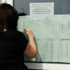 Kobieta w czarnej bluzce przegląda listę kandydatów do szkoły średniej.