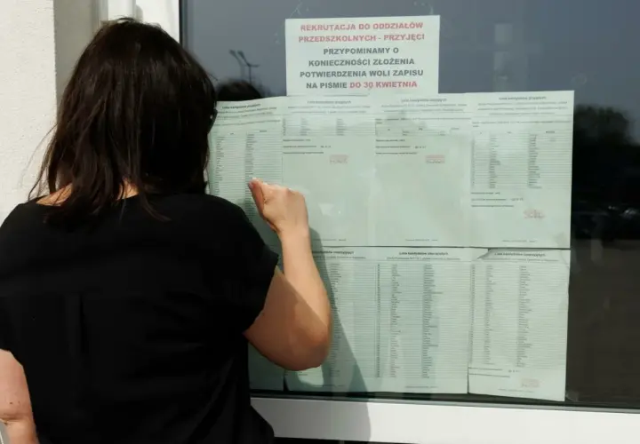 Kobieta w czarnej bluzce przegląda listę kandydatów do szkoły średniej.
