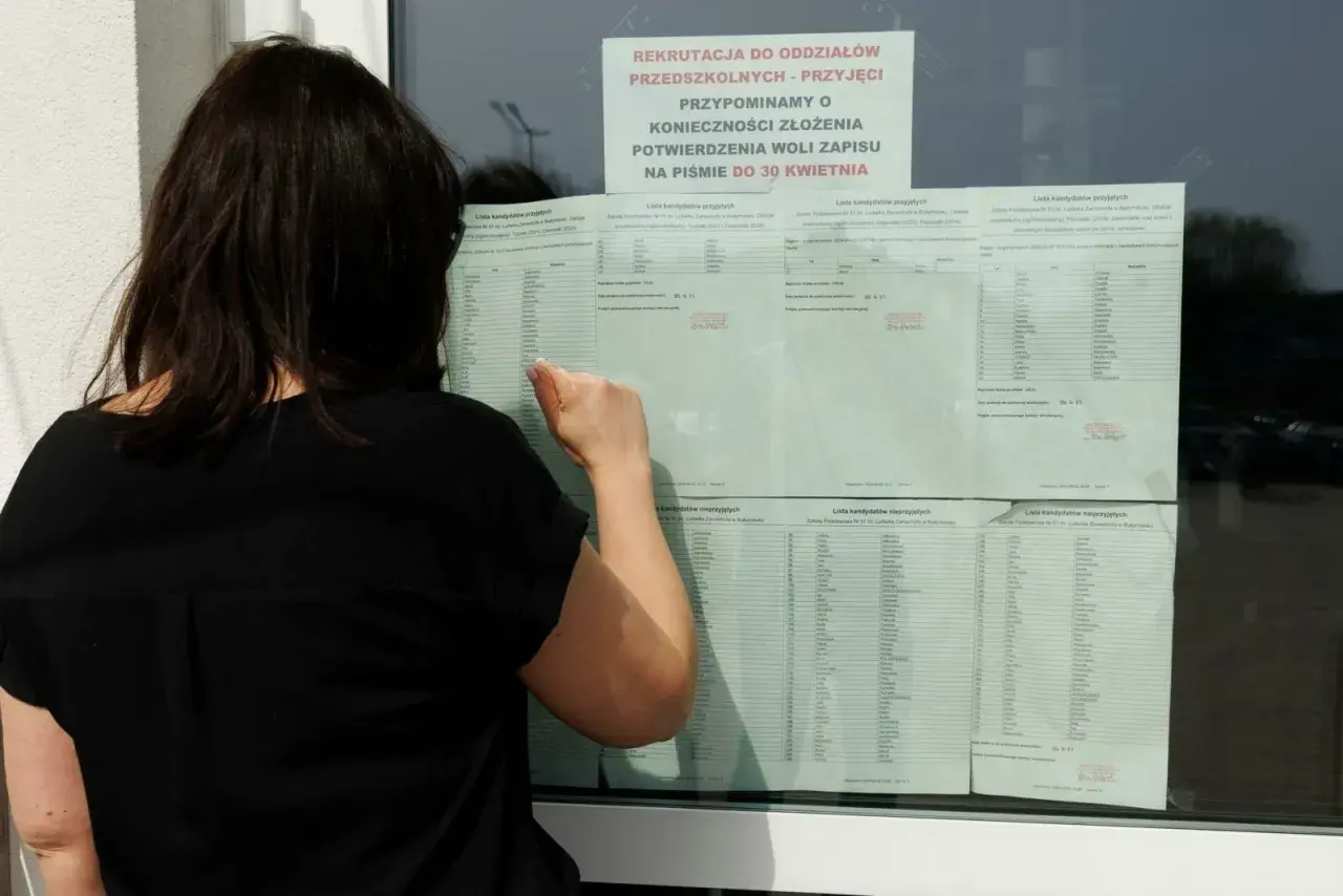Kobieta w czarnej bluzce przegląda listę kandydatów do szkoły średniej.