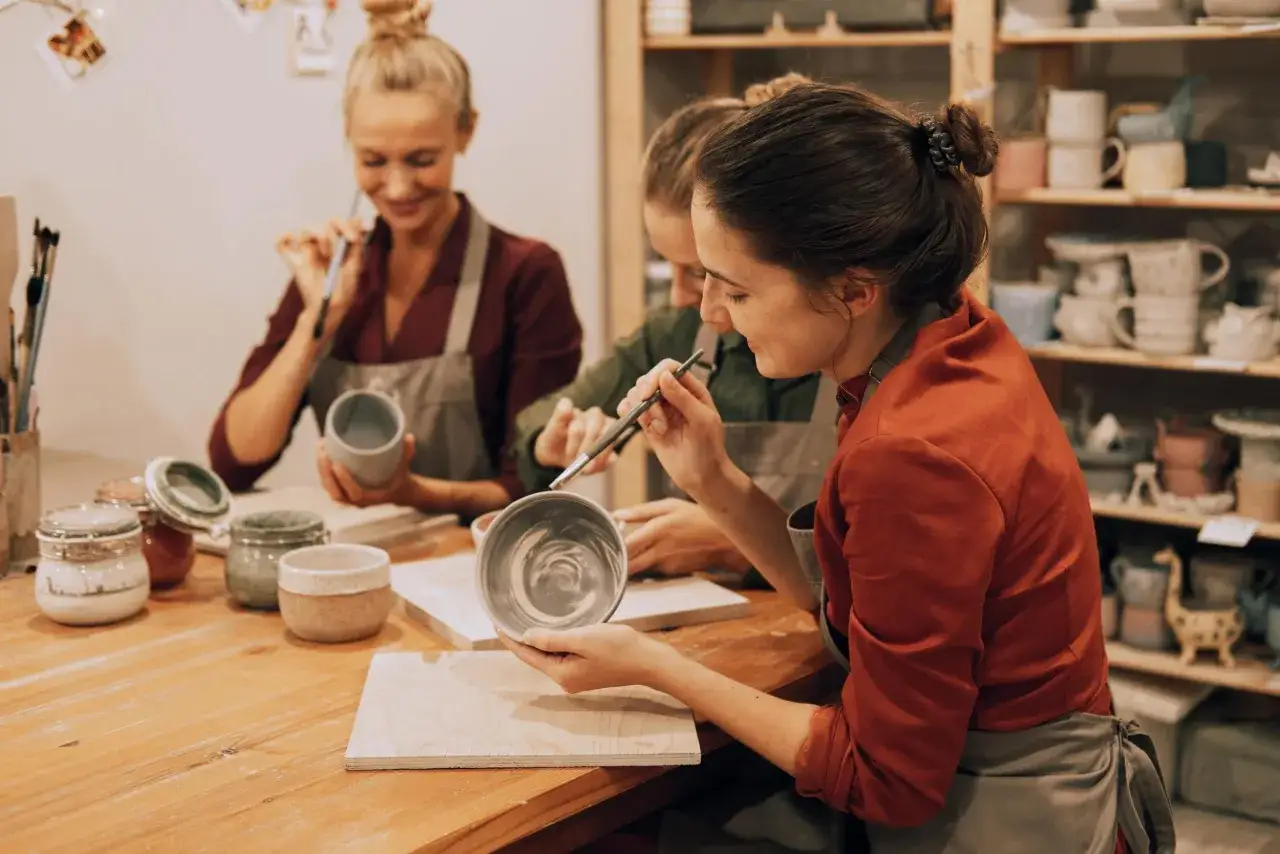 Osoby lepiące ceramikę w pracowni, uśmiechnięte, relaksujące się